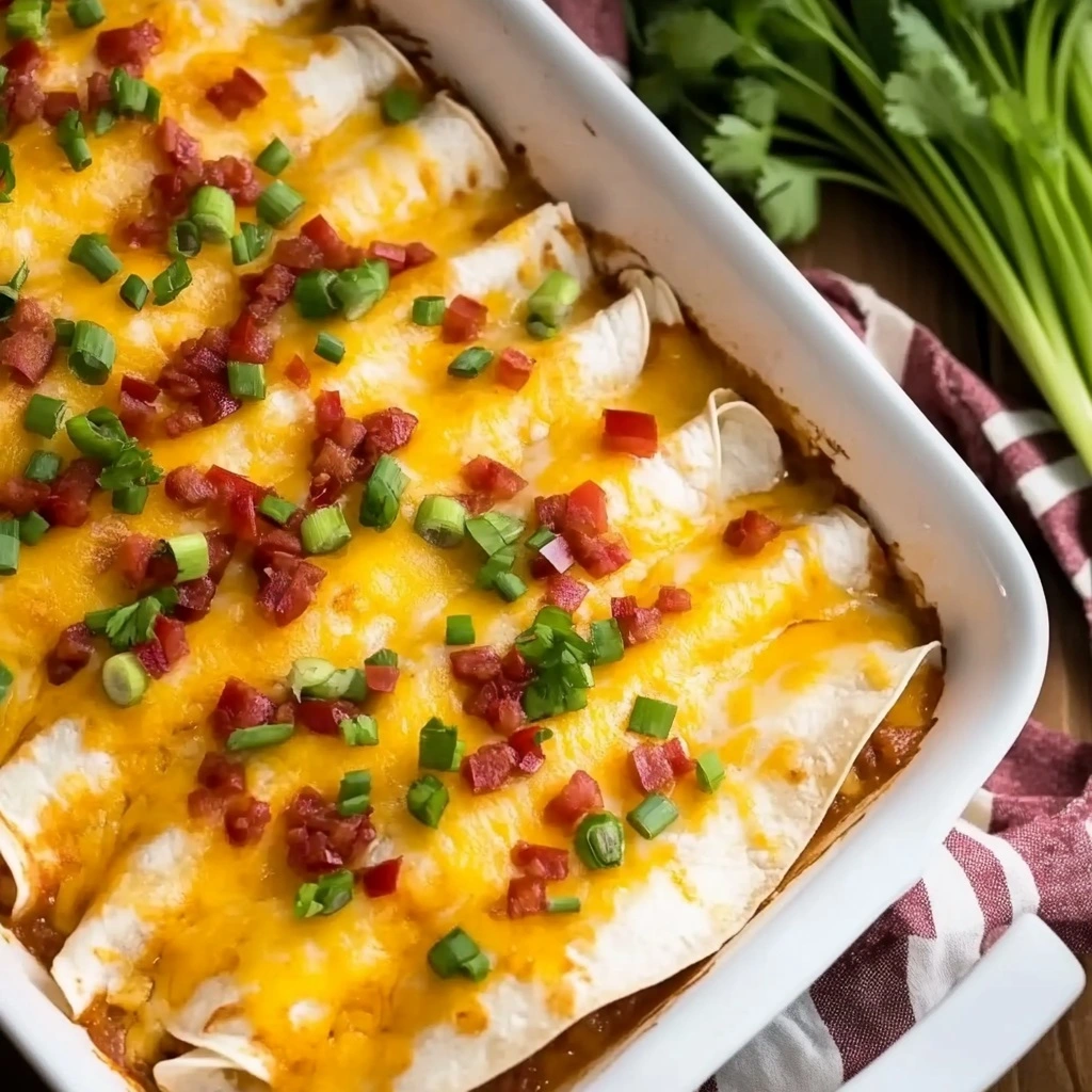 A serving of two breakfast enchiladas on a white plate, topped with a dollop of sour cream and fresh cilantro, with one cut open to show the filling.