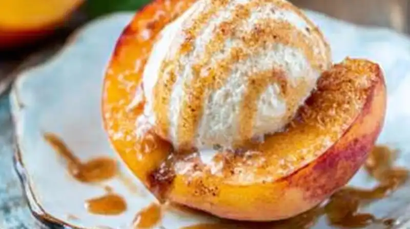 Baked peach halves with melted brown sugar and cinnamon topping served with ice cream