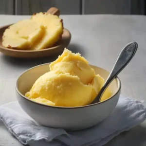 A close-up of a spoonful of pineapple cream, showing the chunks of pineapple suspended in the thick, airy vanilla cream.