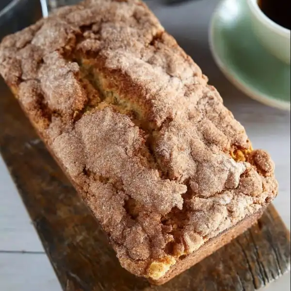 Snickerdoodle_Zucchini_0_result A hand sprinkling a thick layer of cinnamon-sugar mixture over zucchini bread batter inside a loaf pan.