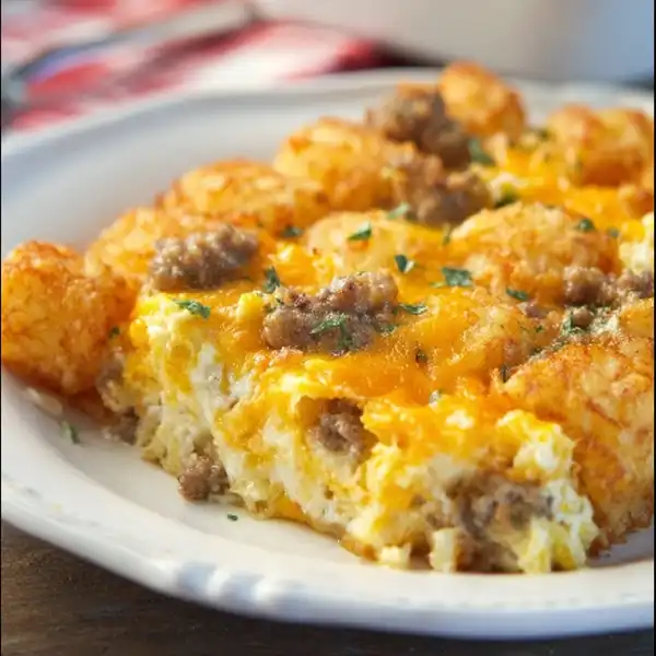 A perfectly golden-brown tater tot sausage casserole in a 9x13 dish, fresh out of the oven, with bubbly cheese and crispy tots.
