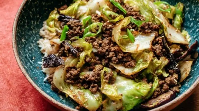 chinese_ground_beef_and_2_result Close-up of sizzling stir-fried cabbage and beef with sesame oil drizzle.