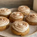 Soft pumpkin cookies topped with creamy cinnamon frosting swirl on a fall platter
