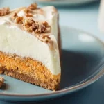 Whole carrot cake cheesecake topped with cream cheese frosting and chopped pecans