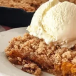 Slice of pumpkin pie crisp with oat pecan streusel and vanilla ice cream