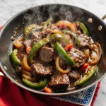 Easy Chinese pepper steak with tender beef and colorful bell peppers in a glossy sauce, sizzling in a wok.